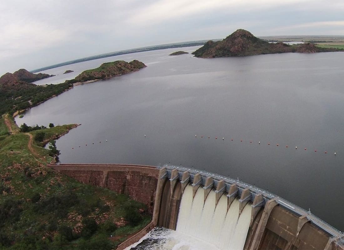 Contact - Aerial View of a Lake with Water Flowing in a Dam Surrounded by Green Foliage in Altus Oklahoma